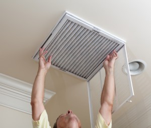 Senior man opening air conditioning filter in ceiling